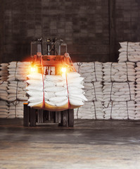 Forklift handling sugar bags for stuffing into a container for export, warehouse operation and safety of proper lighting concept.