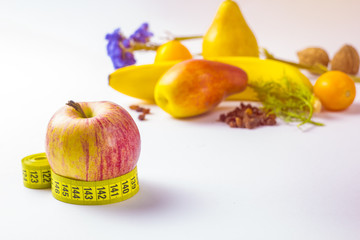 healthy eating, dieting, slimming and weigh loss concept - close up of apple, measuring tape and fruits