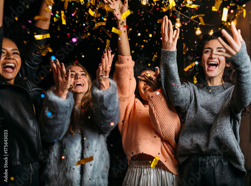 Zdjęcie XXL Plenerowy strzał szczęśliwi przyjaciele. Szczęśliwe kobiety rzuca confetti przy przyjęciem.