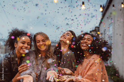 Four beautiful women standing at a terrace under confetti. Poster