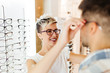 Attractive young couple in optical store buying glasses and smiling