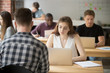 © fizkes - Casual business woman typing on laptop in shared office space surrounded by coworkers. Young female entrepreneur composing email, communicates with clients or business partners, setting appointments.