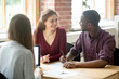 © fizkes - Happy multiethnic couple looking at each other before signing contract in front of female real estate agent. African american man holding pen, preparing to sign the lease for new house or apartment.