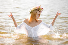 Girl In A White Wet Shirt And Floral Wreath Standing In Water