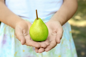 Woman holding ripe pear, closeup