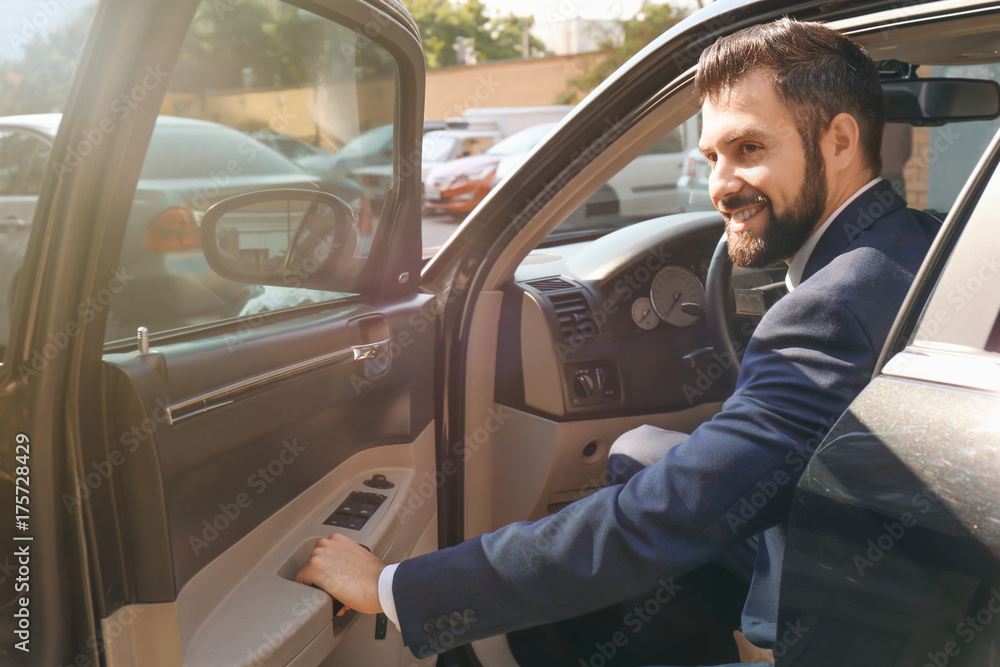 Handsome man in suit getting out of car