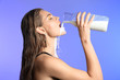 © Africa Studio - Attractive young woman drinking milk on color background