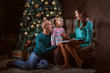 © silkstocking - Young family near the Christmas tree. Mum reads the book to her daughter