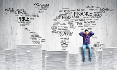 Attractive man sitting on pile of paper documents.