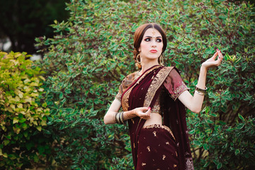 Beautiful young caucasian woman in traditional indian clothing sari with bridal makeup and jewelry and henna tattoo on hands