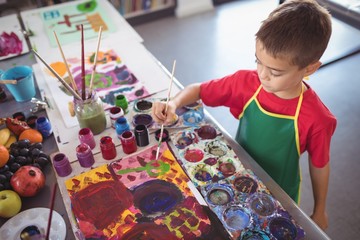 High angle view of boy painting at desk