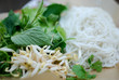 Pile of rice vermicelli with vietnamese herbs: perilla, cilantro, mint, basil, mung bean sprouts. Accompanying plate to vietnamese dishes isolated on neutral background.