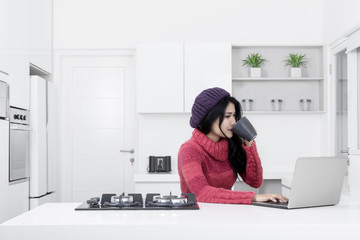 Canvas Print - Pretty woman using a laptop in the kitchen