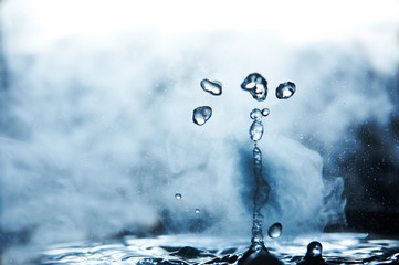 Boiling water splash with steam on black background closeup