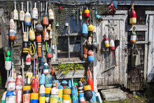 Fishing Wooden House With Nets And Buoys. Colorful Lobster Buoys And Fishnets Hanged On Wooden Wall