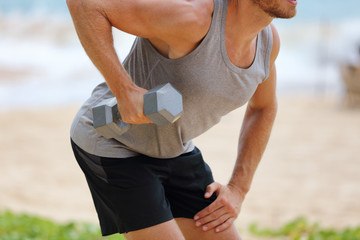 Wall Mural - Bent Over Dumbbell Row Exercise - fitness man doing standing row exercise with one free weight. Bent-over Dumbbell Row or Bent over row. Person exercising on beach outdoors.