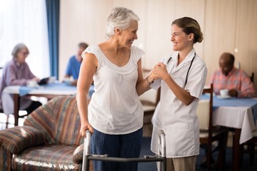 Wall Mural - Smiling senior woman with walker looking at female doctor