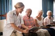 © WavebreakMediaMicro - Smiling female doctor reading book to senior people sitting on