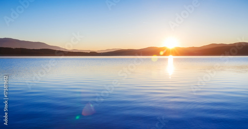 Plakat Cudowny wschód słońca nad scenerią jeziora w kolorach niebieskim i żółtym. Zdjęcie panoramiczne.