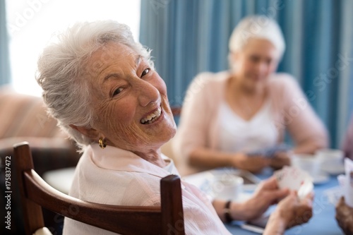 Fotomural Smiling senior woman playing cards with friends