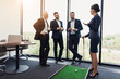 © VadimGuzhva - Three businessmen and business ladies play golf. A woman is holding a golf stick in the dots. Men are watching
