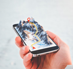 Man holding smartphone with mountains on the screen.