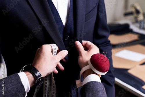 Fotomural Closeup of tailor fitting bespoke suit to model, hands with tape measure and pin