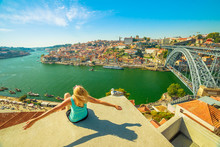 Carefree Woman With Open Arms Looking Picturesque Porto And Ribeira District Skyline. Aerial View Of Dom Luis I Bridge On Douro River, Vila Nova De Gaia, Portugal. Female Tourist Enjoying In Sunny Day