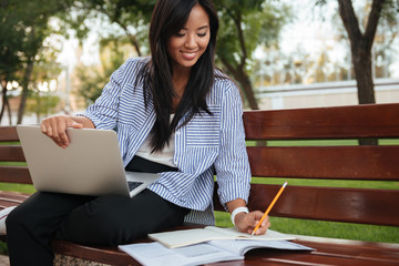 Poster - Close-up photo of young smiling asian female student, taking notes, holding laptop, outdoor