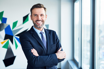 businessman in office looking at camera with arms crossed