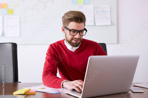 Plakat Kreatywnie biznesmen pracuje z laptopem w biurze