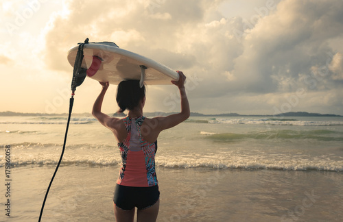 Zdjęcie XXL Tylni widok młoda kobieta surfingowiec z białym surfboard odprowadzeniem morze