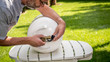 In the backyard a man replaces the cap on a propane bottle