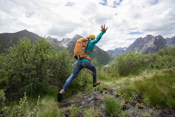 backpacking woman jumping in mountains