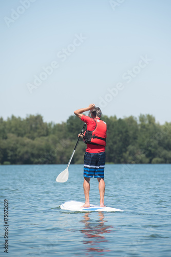 Plakat człowiek, ciesząc się jazdą po jeziorze z paddleboard