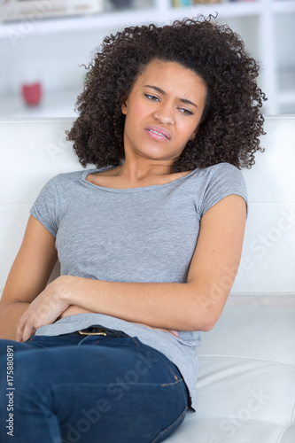Zdjęcie XXL dorosła kobieta siedzi na kanapie z bólem w żołądku