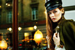 © Victoria Fox - Outdoor portrait of young beautiful fashionable woman posing in street. Model wearing stylish leather hat, green jacket. Lights and reflections on background. Copy, empty space for text