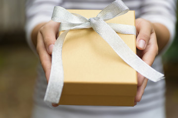 Golden gift box in hand for giving in holidays