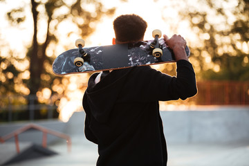 Sticker - Back view of a male teenager guy holding skateboard