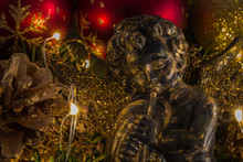 Christmas Angel On Abstract Blurry Background And Golden Lights, Fir Cone And Red Christmas Balls