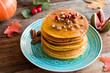 Pumpkin pancakes with pecan nuts, red berries and honey on a blue turquoise plate. Seasonal autumn food