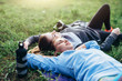 Two young sportswomen laying on grass with eyes closed relaxing after outdoor workout