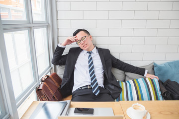 Wall Mural - Portrait of an upset businessman at desk in coffee shop. Asian businessman being depressed by working in office.