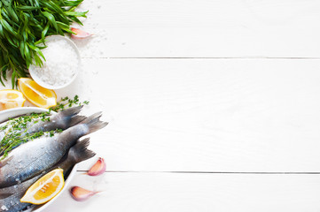 White wooden background with fresh raw fish and ingredients