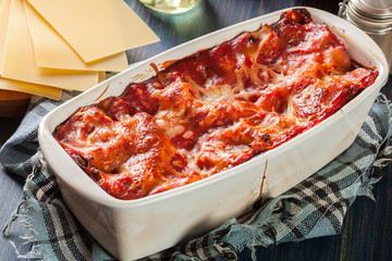 Wall Mural - Hot tasty lasagna with spinach in ceramic casserole dish