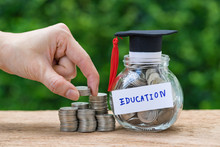Woman Hand Holding Stack Of Coins Money And Glass Jar With Full Of Coins And Graduates Hat Label As Education, Education Or Savings Concept