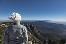 Woman Looking Out At The Mountains And Below From A Tall Peak