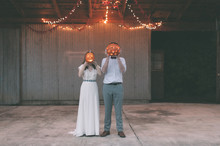Wedding Couple With Jack-O-Lantern Decorations Over Their Faces
