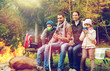 © Syda Productions - happy family sitting on bench at camp fire