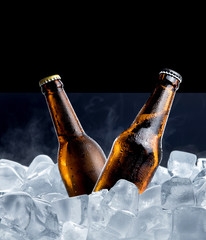 Wall Mural - Cold bottle of beer with drops in ice cubes isolated on black background